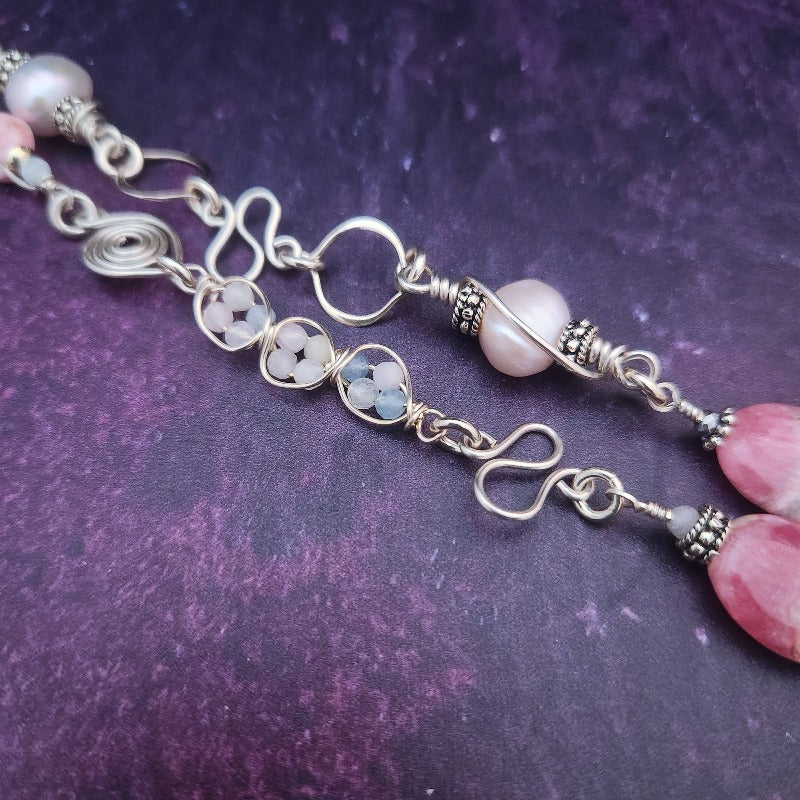 Crafted from luxurious sterling silver, our KITTEN BELL necklace features a unique design with Rhodochrosite and Freshwater Pearls, making it a one-of-a-kind accessory. Wear it as a stylish fashion piece or as a subtle nod to your pet or alternative lifestyle. Either way, you'll exude elegance and sophistication.