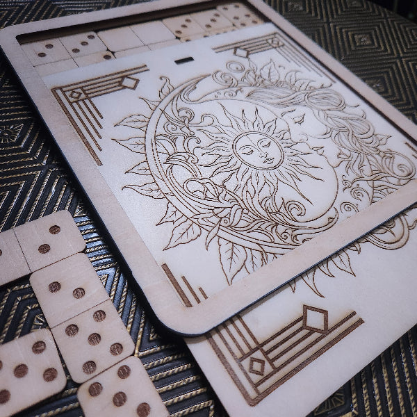 A wooden board game set featuring a decorative engraved board with a sun and moon design, shown with wooden dominoes on a patterned dark surface.