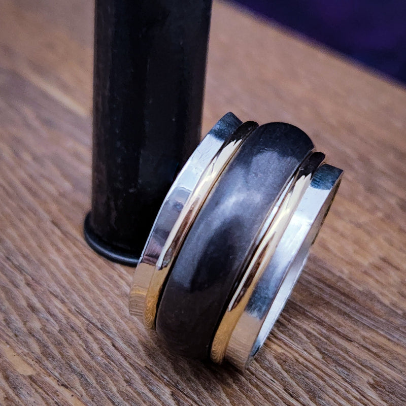 Stack of silver rings with gold accents on a wooden surface