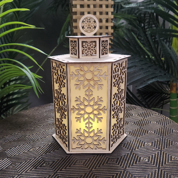 Decorative lantern with snowflake patterns on a textured surface with plants in the background