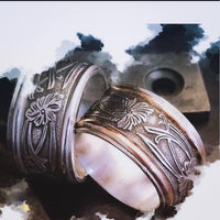 Two intricately designed rings on a textured surface