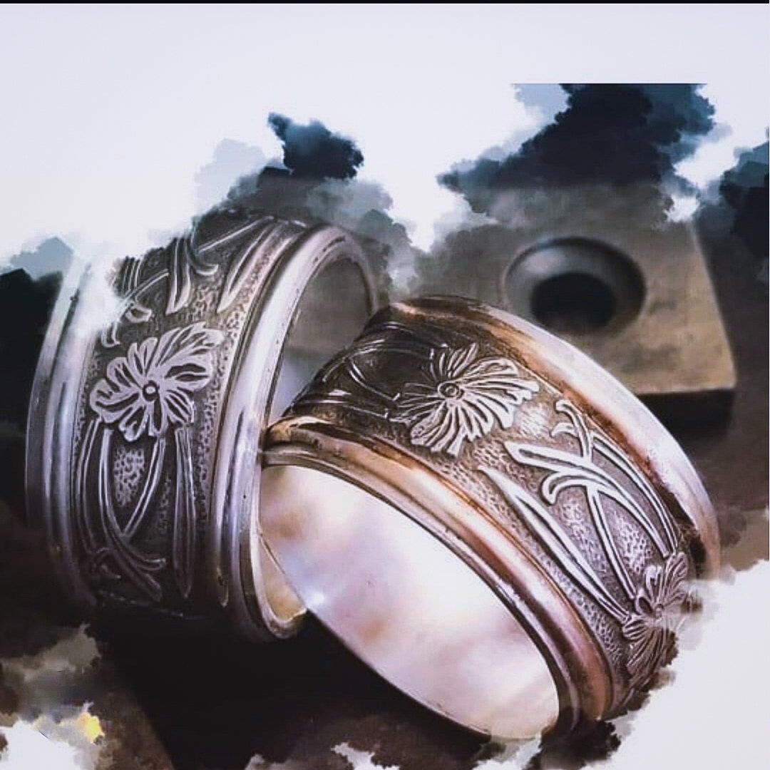 Two intricately designed rings on a textured surface