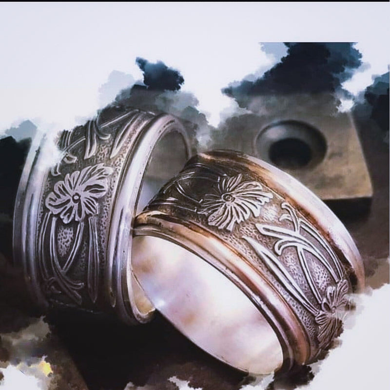 Two intricately designed rings on a textured surface