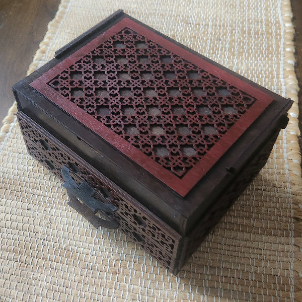 Decorative wooden box with intricate lattice design on a woven mat