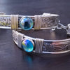 Two silver bracelets with blue gemstones on a dark surface