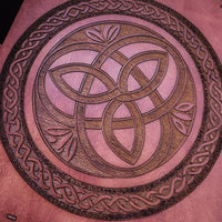 Decorative circular design with interwoven patterns on a teak wood background