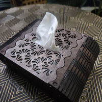 Decorative tissue box with intricate cut-out design on a textured surface