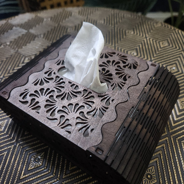 Decorative tissue box with intricate cut-out design on a textured surface