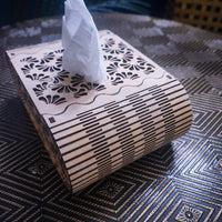 Wooden tissue box with laser-cut design on a textured surface