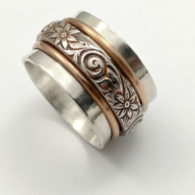 Silver and rose gold ring with intricate patterns on a white background