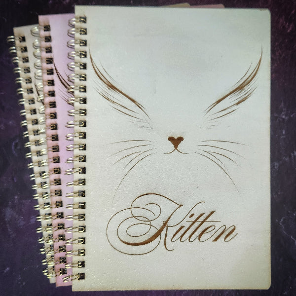 Notebook with 'Kitten' design on a dark textured surface