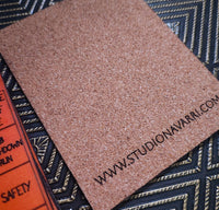 A square brown textured sample card with the printed website URL 'WWW.STUDIONAVARRI.