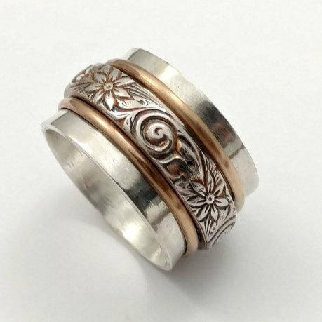 Created by My Secret Heart Studios, this substantial artisan has spinning bands of sterling floral pattern and 14K gold-filled wire encircles a wide, hefty band of brushed sterling silver.