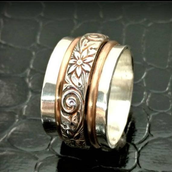 Created by My Secret Heart Studios, this substantial artisan has spinning bands of sterling floral pattern and 14K gold-filled wire encircles a wide, hefty band of brushed sterling silver.