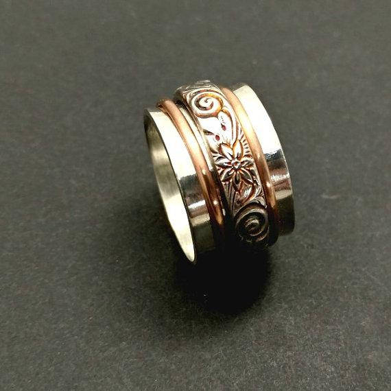 Created by My Secret Heart Studios, this substantial artisan has spinning bands of sterling floral pattern and 14K gold-filled wire encircles a wide, hefty band of brushed sterling silver.