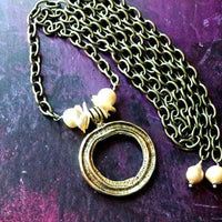 THE 5th AVENUE LARIAT is bold and dramatic, and will definitely get some attention. A large circular disc attached to gold Brittanium chain with both wafer and large freshwater pearls. Simply place the circle where you want it, wrap the chain around your neck and slide the ends thru the circle. Voila! Instant Fashionista!