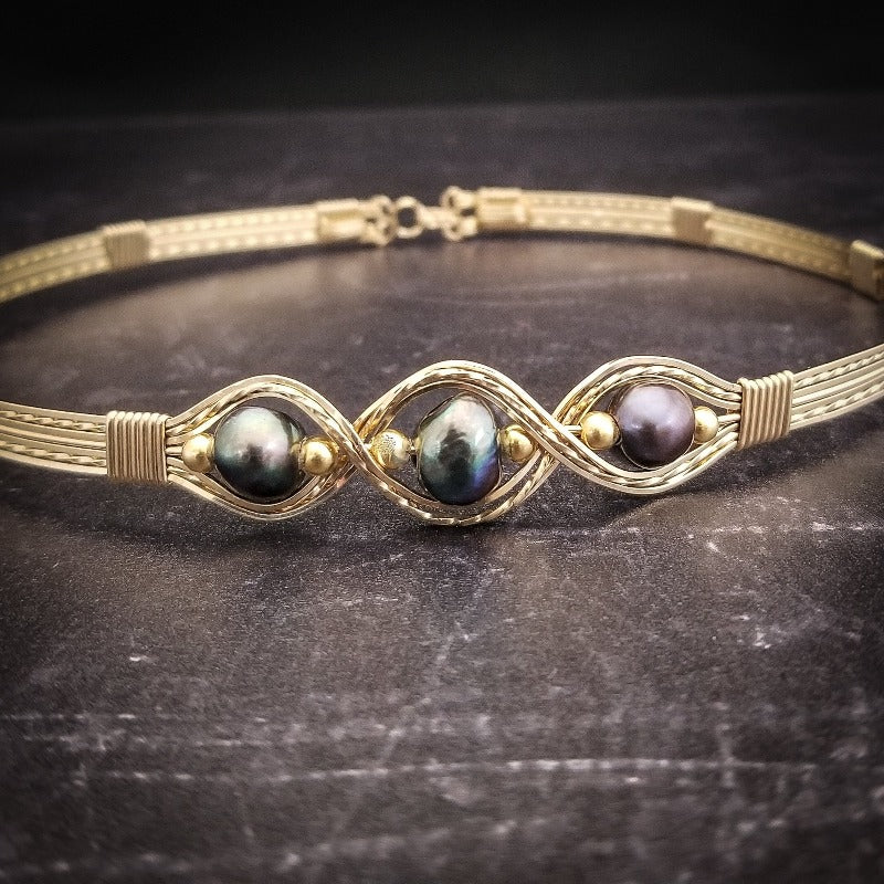 Elegantly crafted with 14k gold filled wire and large freshwater pearls of a peacock hue, this collar is a bold yet delicate accent to add femininity to any outfit. Secured with a hook and eye closure. From everything from your jeans and tee to your wedding dress!
