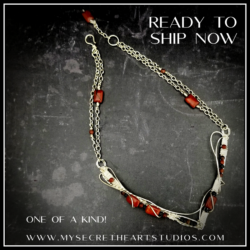 This collar is hand crafted and wrapped with strands of luscious sterling silver wire and embellished with Red Jasper and Black Onyx. Gemstones and accent beads are incorporated securely into the wire work. Flowing curves soften the hard lines of the metals and an asymmetrical flair makes this an unusual and dramatic addition to your private collection.