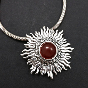 Dramatic Sunburst pendant with hand set with a  gemstone cabochon in your choice of black onyx, carnelian or moonstone. The pendant is sterling silver, the bail is silver plated. Can be worn as a pendant on a chain, or slide onto most all or our artisan collars.