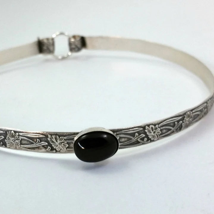 Hand crafted in the floral pattern Soft and Sweet, this artisan collar is hand crafted in sterling silver with a Black Onyx cabochon hand set into a sterling silver bezel. 