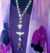 The scent of lavender and roses in the evening breeze. Golden sandals on the garden path. This garden themed necklace will glow with the reflection of the evening sun and garden torches. A chain of golden soft cornered squares and circles, a butterfly, a lunar moth and a sweet hummingbird medallion, all intermingle with faceted crystals in clear, pale blue, and aquamarine colors. Finished with a large, faceted blue crystal.